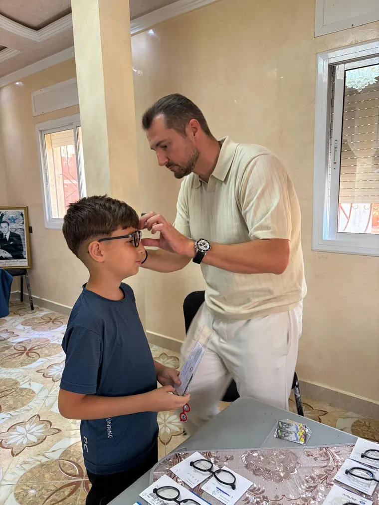 Un opticien ajuste une monture imprimée sur un jeune garçon